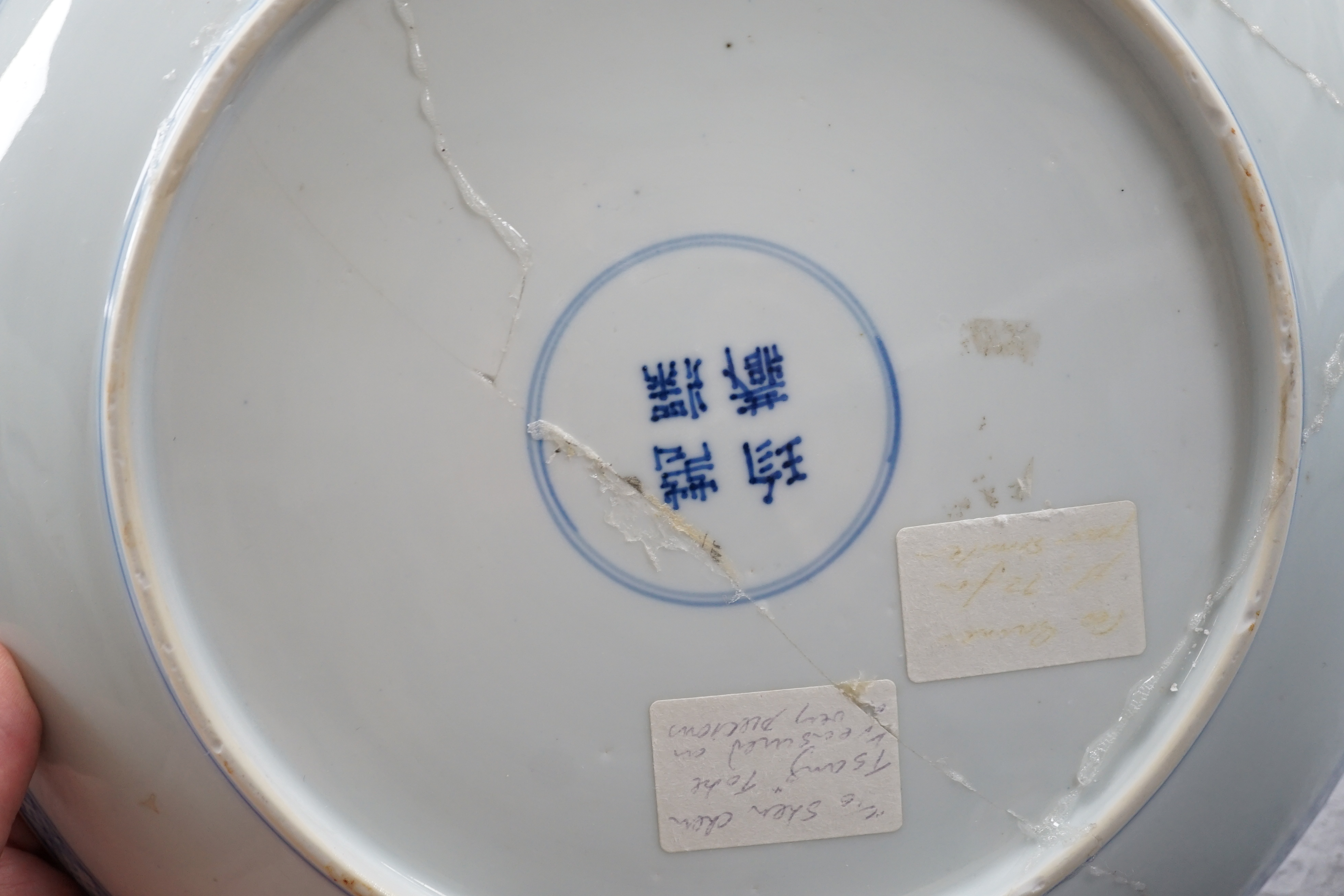 A Chinese blue and white dish, Kangxi period, broken and messily reglued